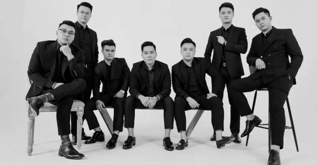 Stylish group of men in black and white suits posing in a studio. Elegant and professional.