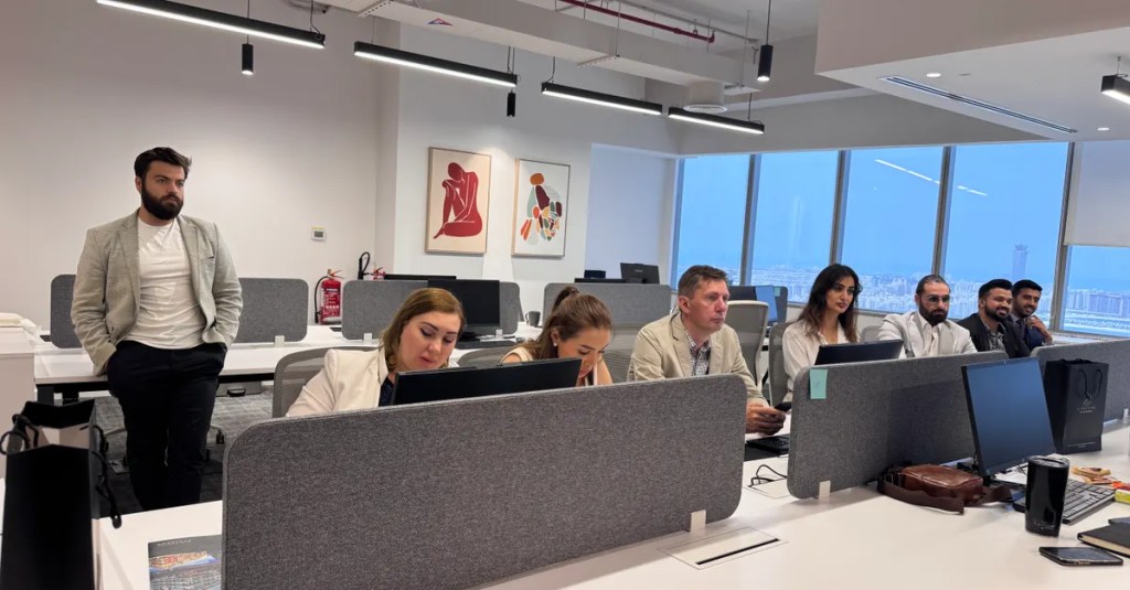 Team of professionals working in a modern office setting with computers and open workspace.