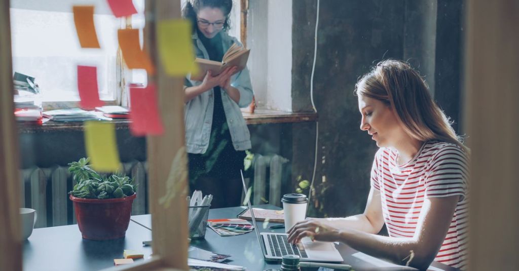 Two women engaged in creative work, collaborating in a stylish office space.