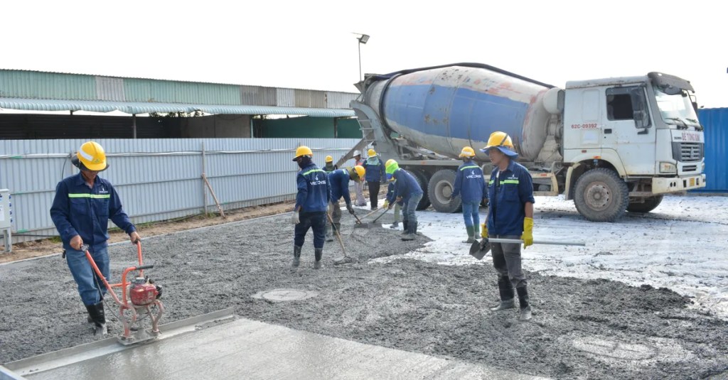 Team of workers pouring cement from a mixer truck on a construction site, ensuring proper leveling.