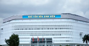 Contemporary architecture of a university cultural center with flags in front, cloudy sky above.