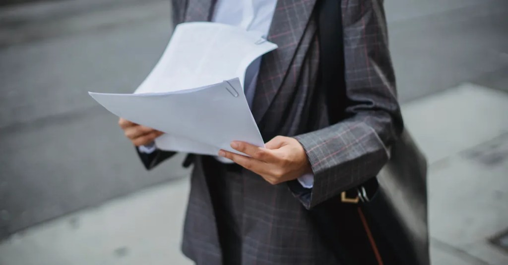 Professional businesswoman reviewing documents outdoors in a city environment.
