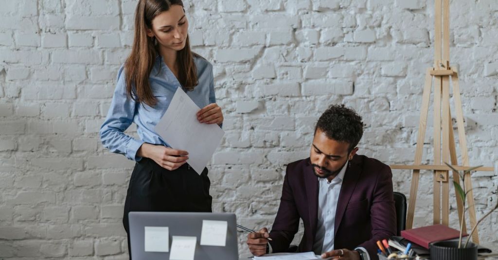 Two professionals in an office discussing documents while working together. Ideal for business themes.