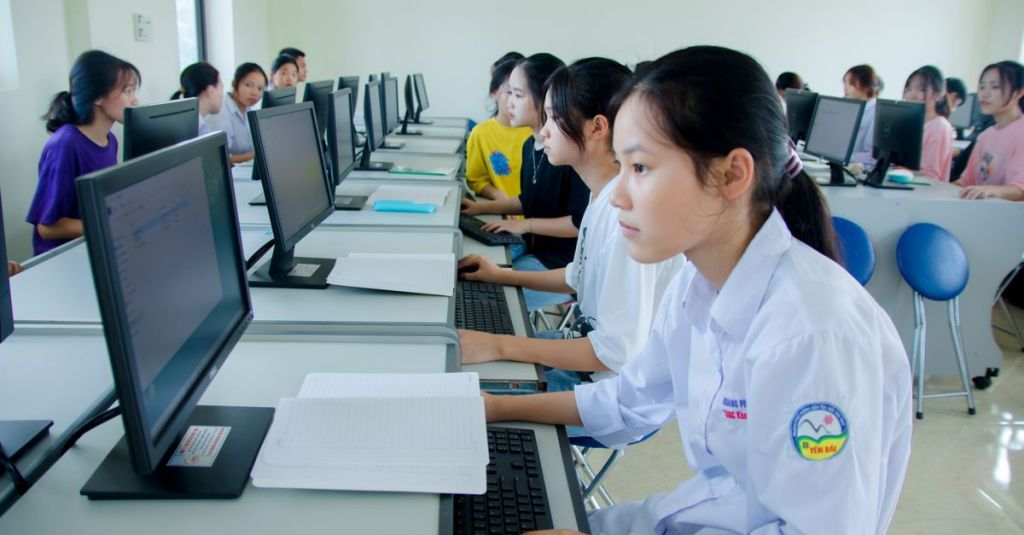 Người học làm việc tại phòng máy tính trong bối cảnh học tập công nghệ và phối hợp nhóm.