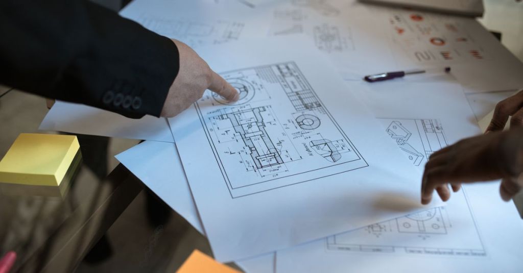 Engineers discussing blueprints at a workspace, focusing on teamwork and architecture design.