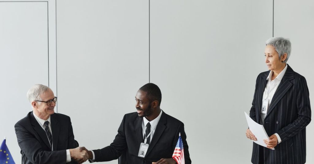 Multinational business meeting with agreement signing, featuring diverse professionals and flags.