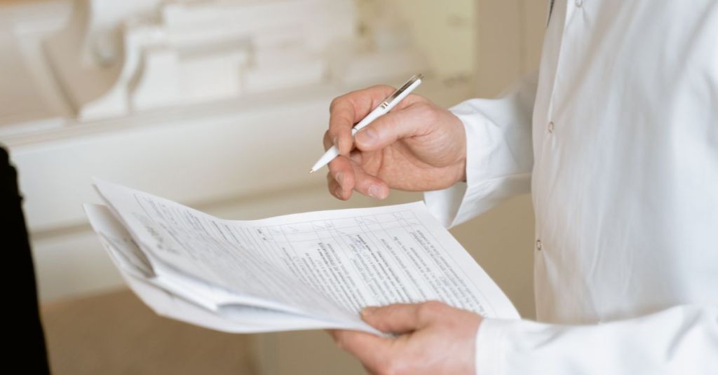 A doctor holds and reviews medical documents, demonstrating careful examination and professionalism.