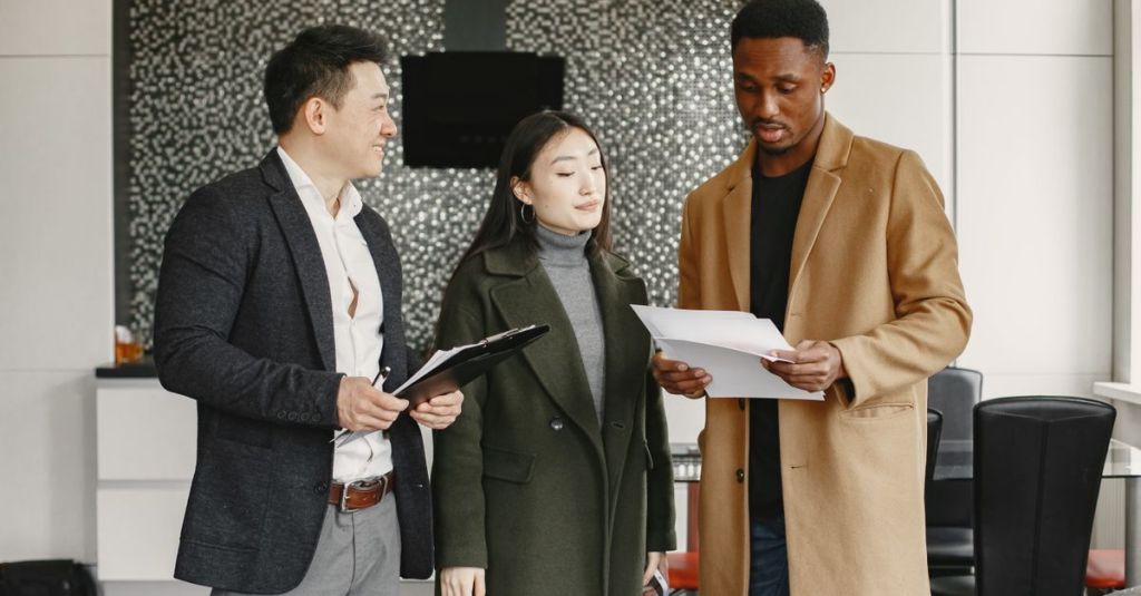 Three colleagues reviewing business documents in a modern office setting.