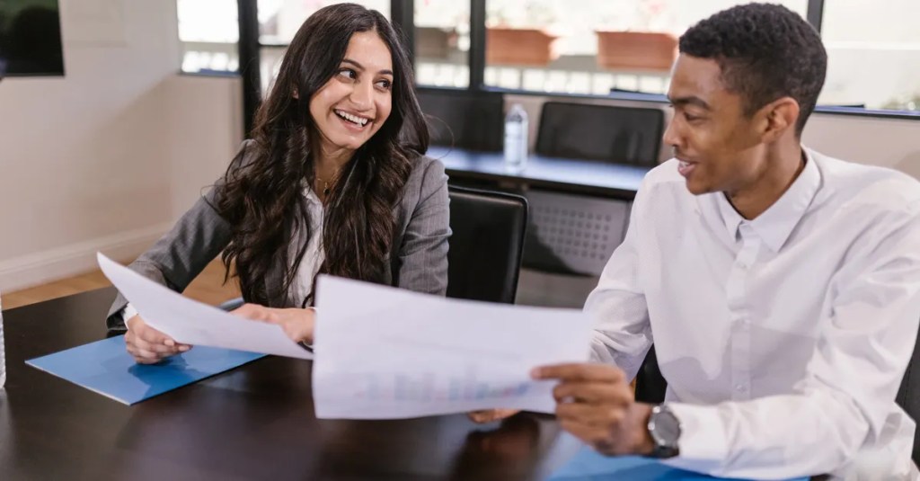 Two colleagues discussing business analytics in a modern office environment, fostering teamwork and diversity.