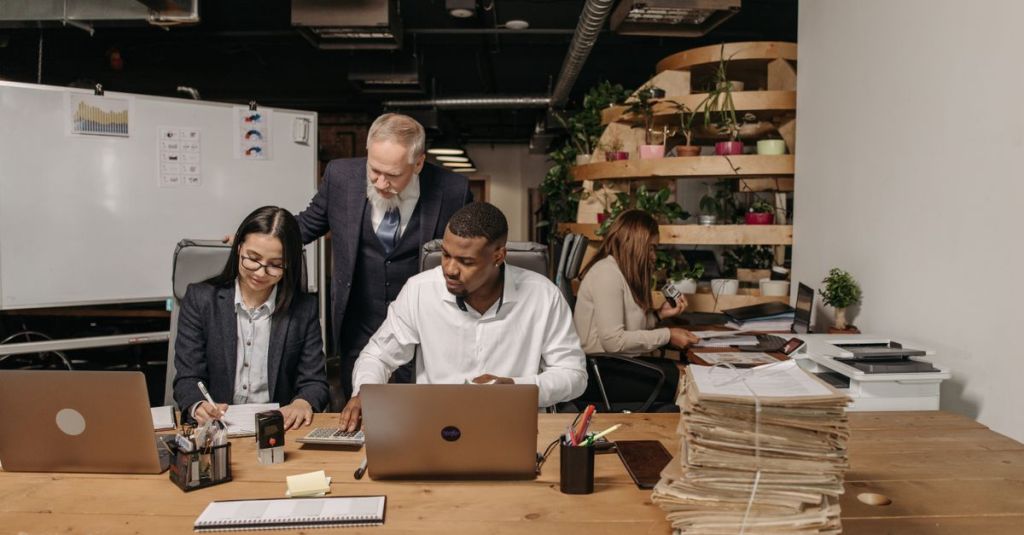 Team of professionals working collaboratively in a modern office environment with documents and laptops.