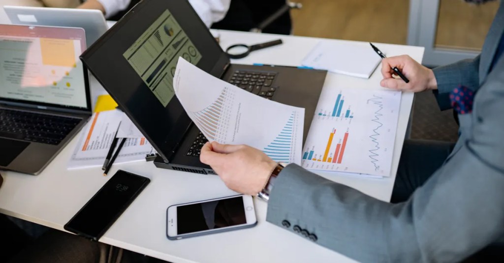 Professionals analyzing charts and graphs on laptops during a business meeting.