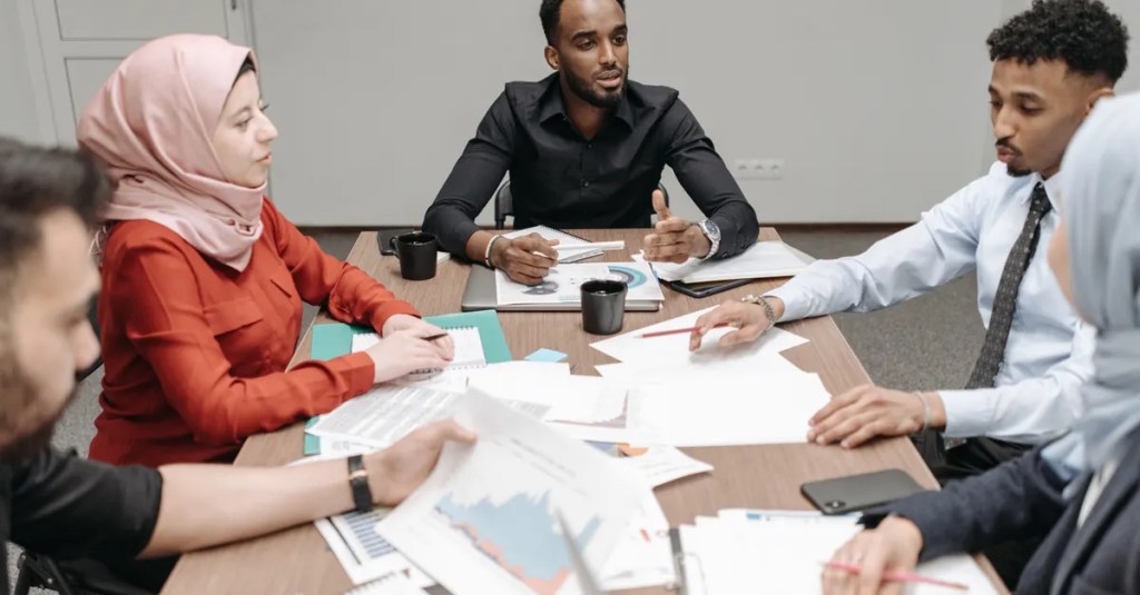Multicultural team discussing business reports around a table indoors.