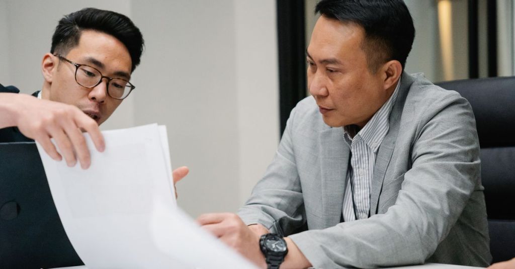 Two professional men engaged in a focused discussion in a contemporary office environment.