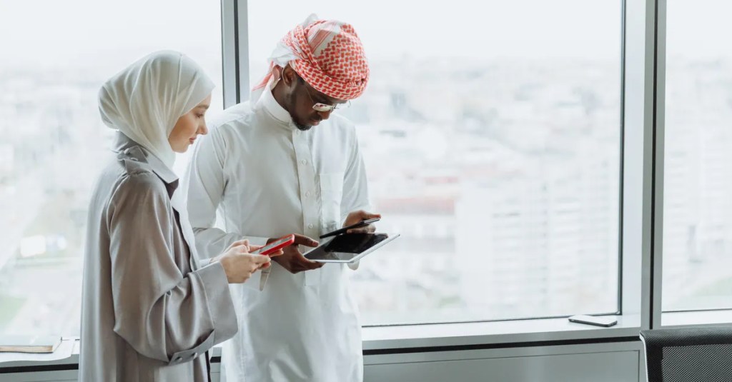 Middle Eastern colleagues collaborating in a modern office setting with digital tablets.