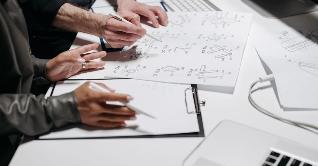 Team members analyzing technical schematics on office workspace. Ideal for business and engineering concepts.