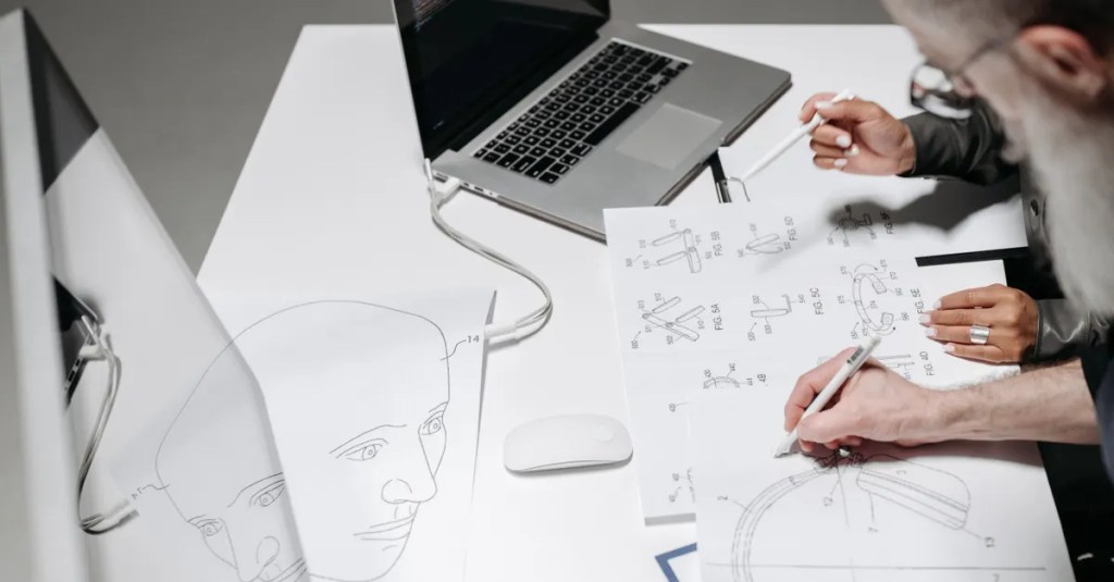 Team working on detailed technical drawings at a modern office desk.