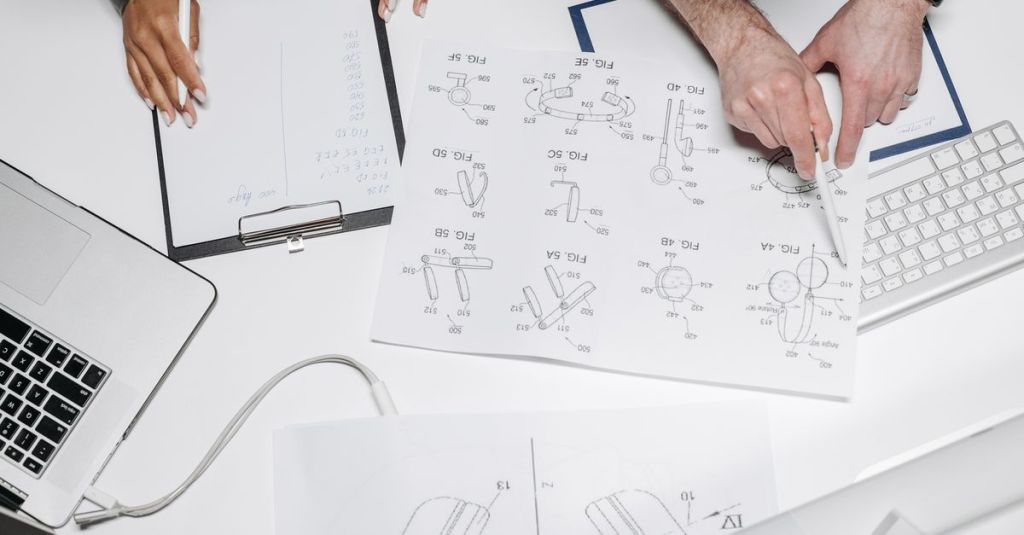 Two professionals collaborate on product design with technical diagrams and notes.