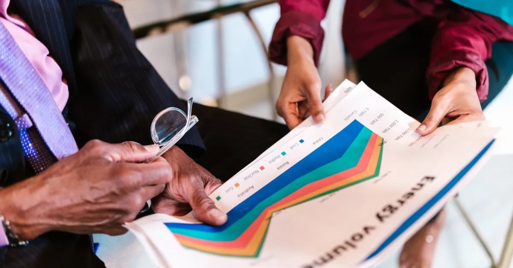 Two professionals reviewing detailed energy consumption charts in an office setting.