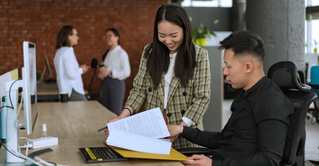 Professionals engaged in teamwork at a modern office desk reviewing documents.