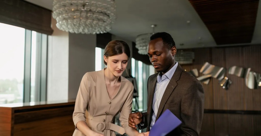 Two professionals reviewing documents during a business meeting in a modern office setting.