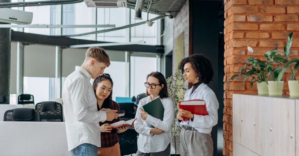 A diverse team of professionals collaborates in a modern office setting, exchanging ideas.