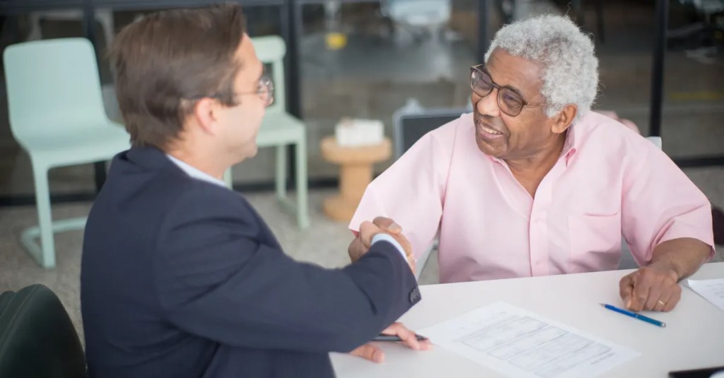 Two businessmen shaking hands in an office, sealing a deal.
