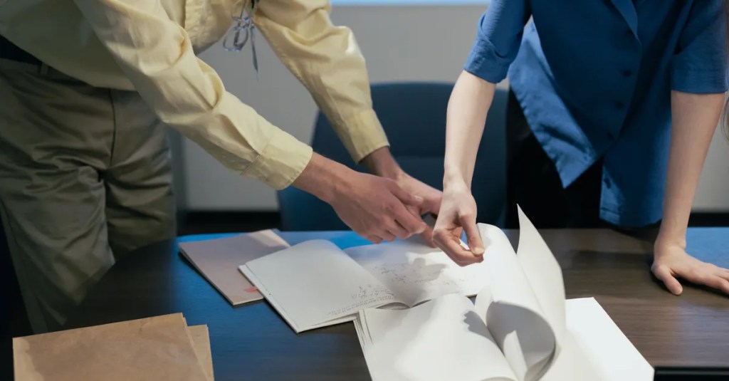 Two professionals engaged in a workplace discussion reviewing documents.