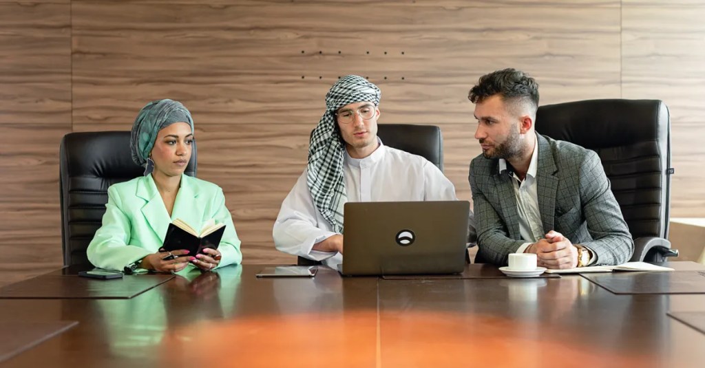 Three professionals in a diverse, multicultural meeting setting discussing business planning.